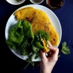 A piece of banh xeo wrapped in lettuce and herbs.