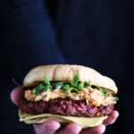 A hand holding a vegan beetroot burger.
