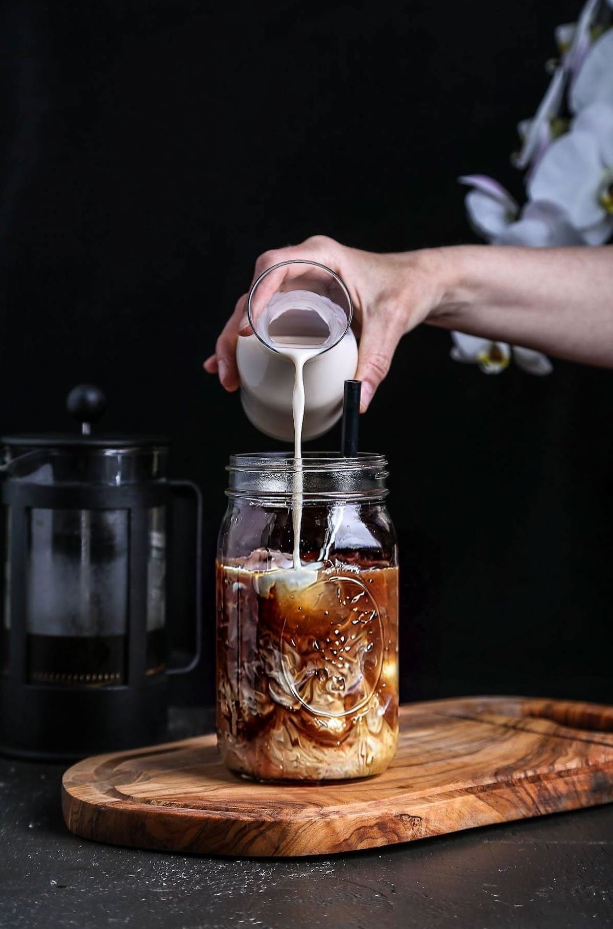 Vegan creamer being poured into cold brew coffee.