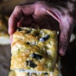 A hand holding a piece of quick and easy focaccia bread.