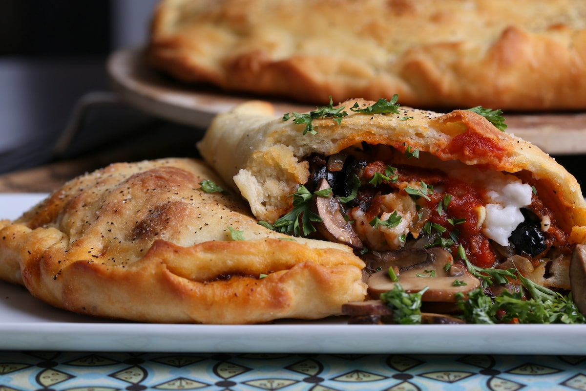 A homemade vegan calzone, cut open to show its interior.