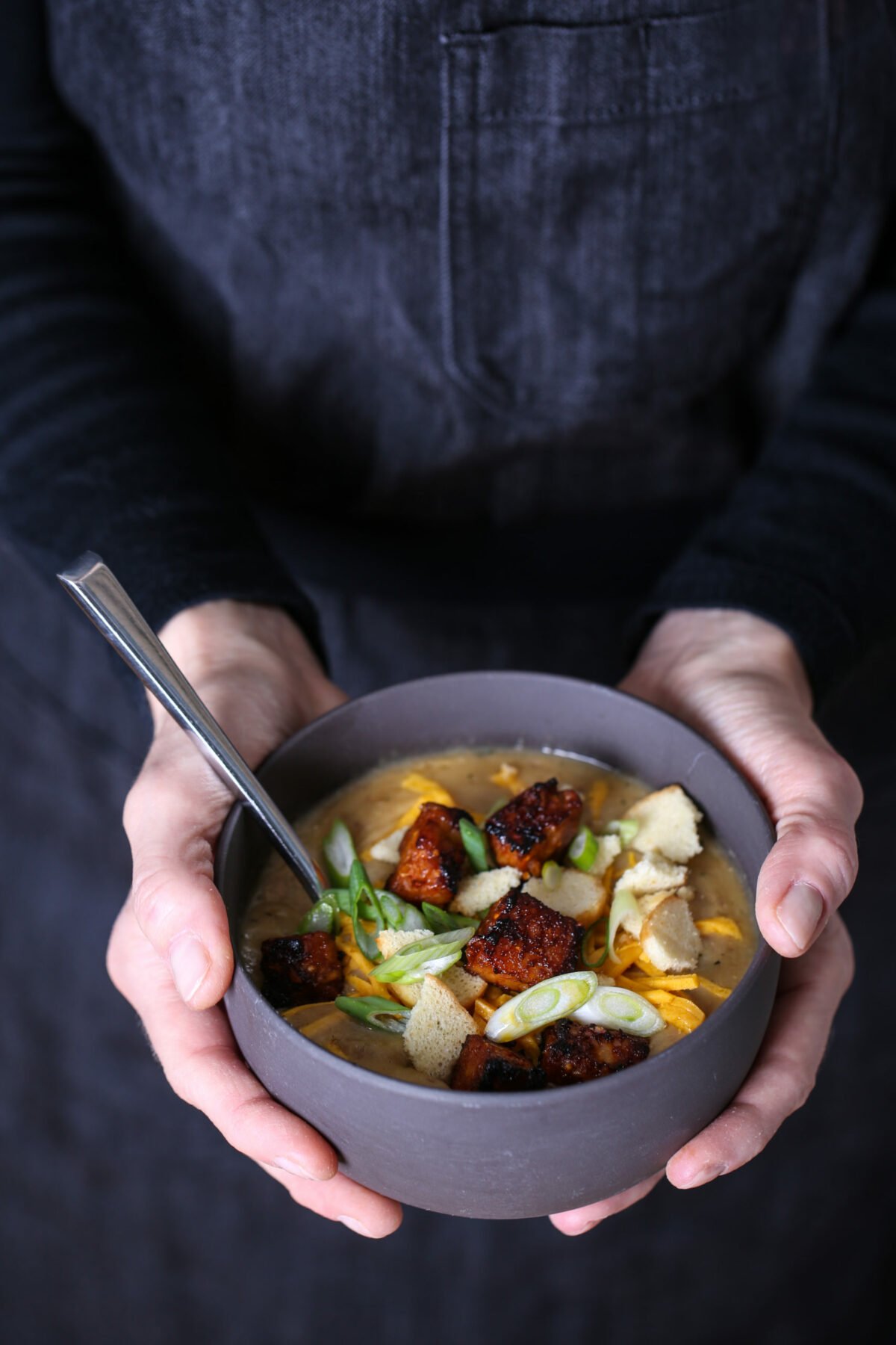 Two hands holding a bowl of vegan potato soup.