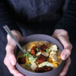 A bowl of hearty potato soup with tempeh cubes and vegan cheese.