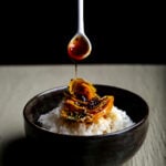 Teriyaki sauce being drizzled over a bowl of golden beets and rice.