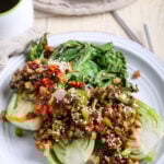 Grilled bok choy on a white plate with chopped oyster mushrooms.