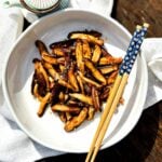A bowl of sautéed shiitake mushrooms with chopsticks.