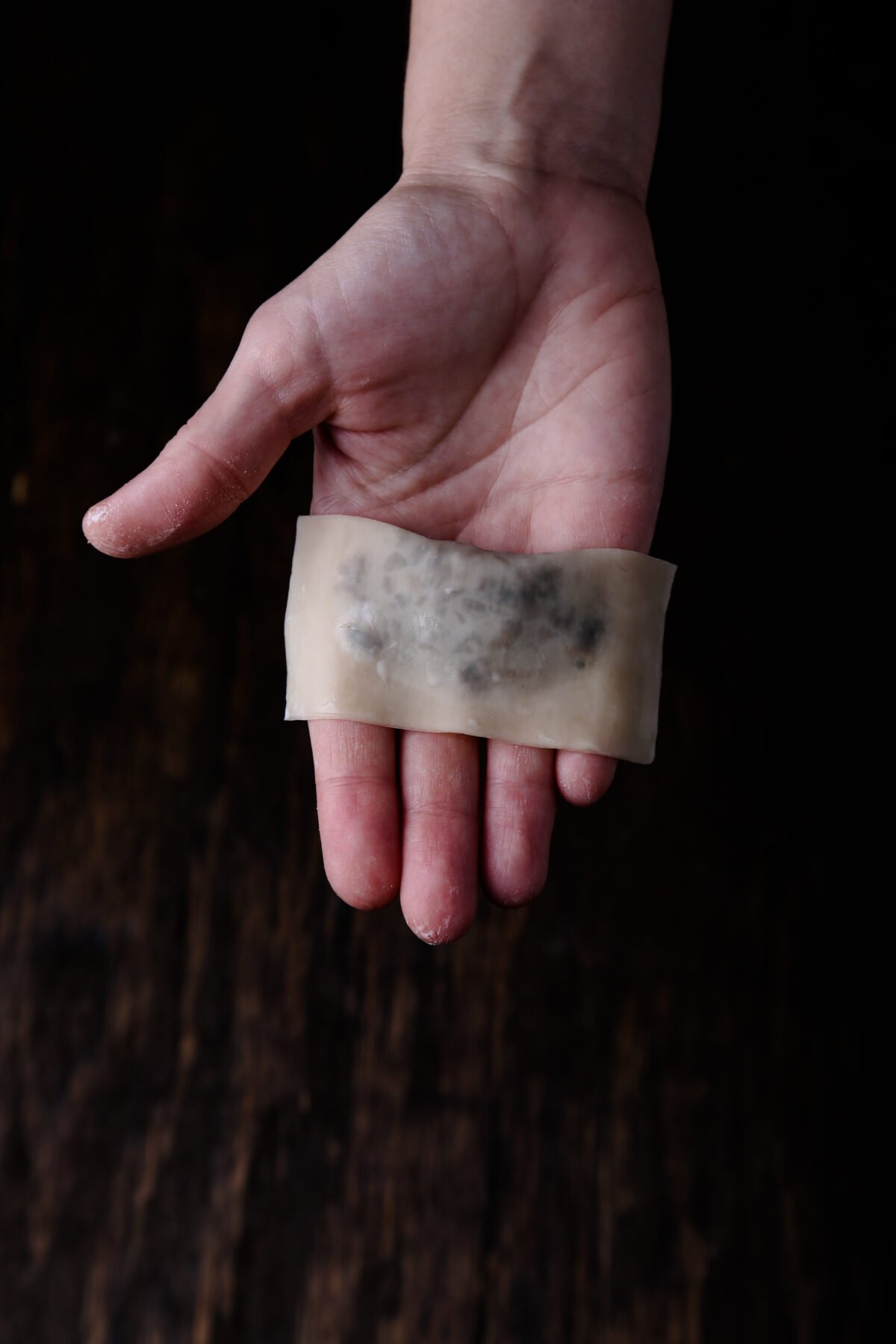 A folded wonton in the palm of a hand.