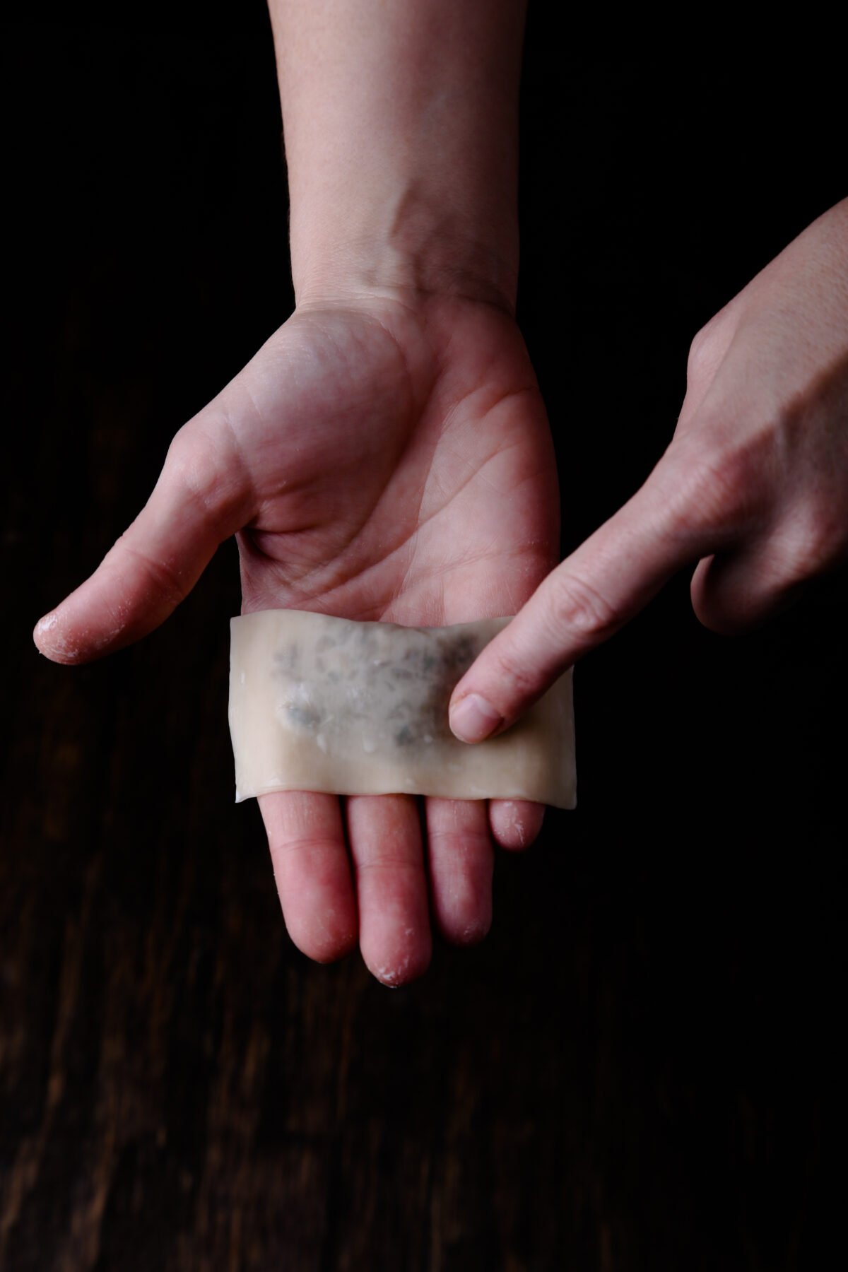 A hand in the process of folding a wonton.