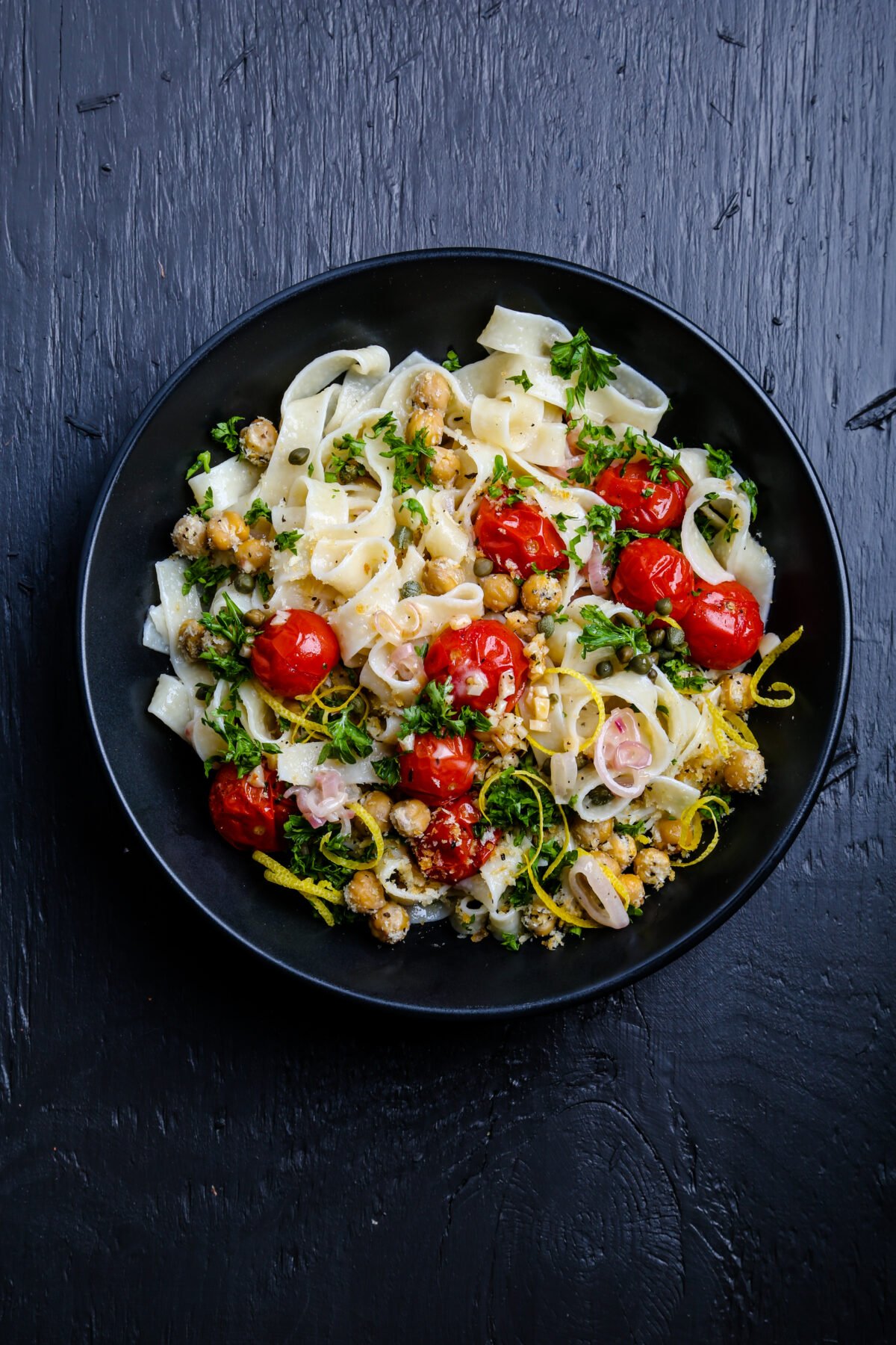 Pasta with roasted tomatoes and chickpeas and lemon garnish.