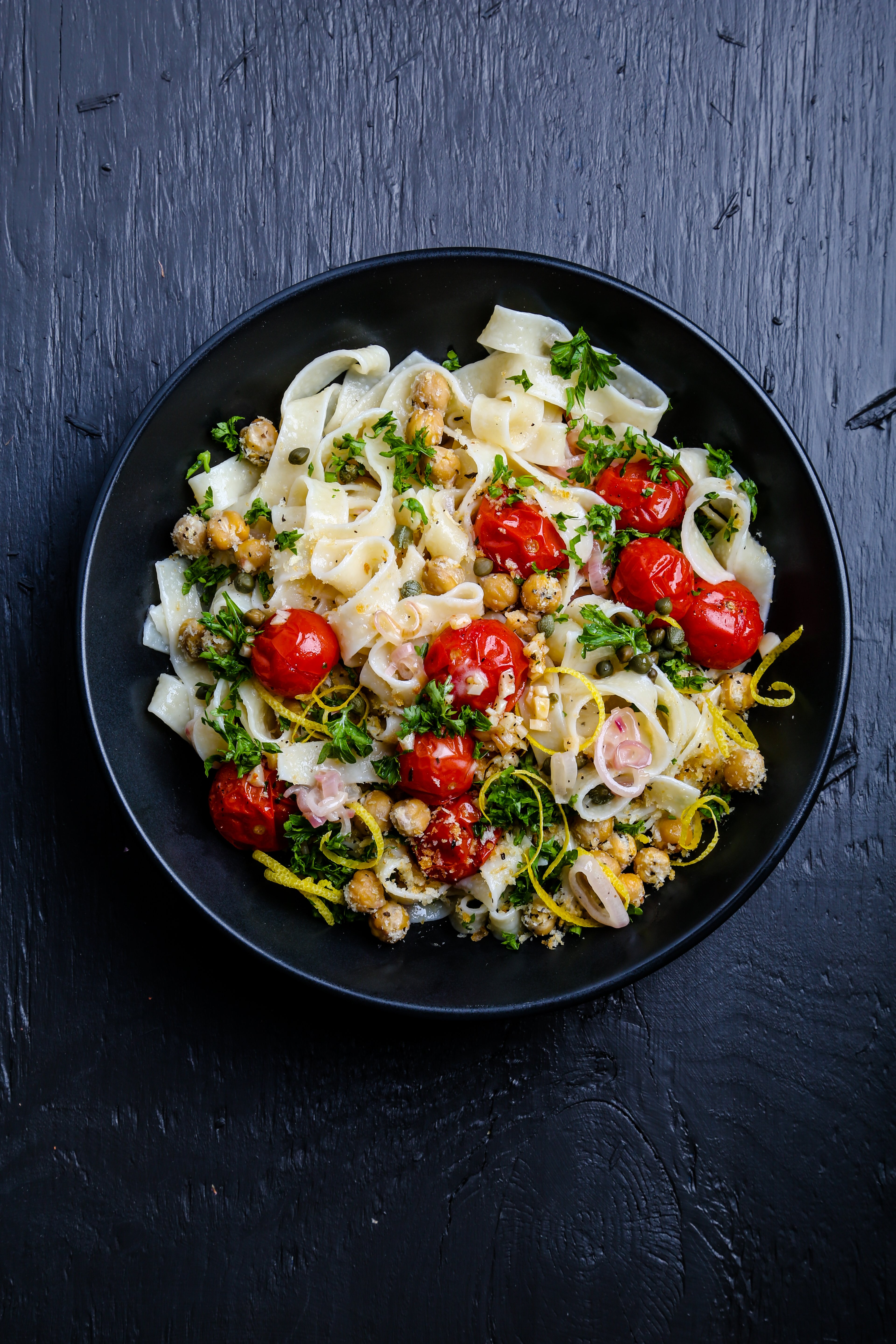 Pasta with roasted tomatoes and chickpeas and lemon garnish.