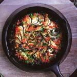 Spiral ratatouille in cast iron skillet with tomatoes, eggplant, zucchini, and oil-cured olives.
