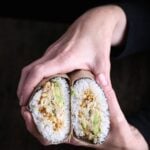 A sushi burrito with vegan crab, spicy sriracha peas, and avocado.
