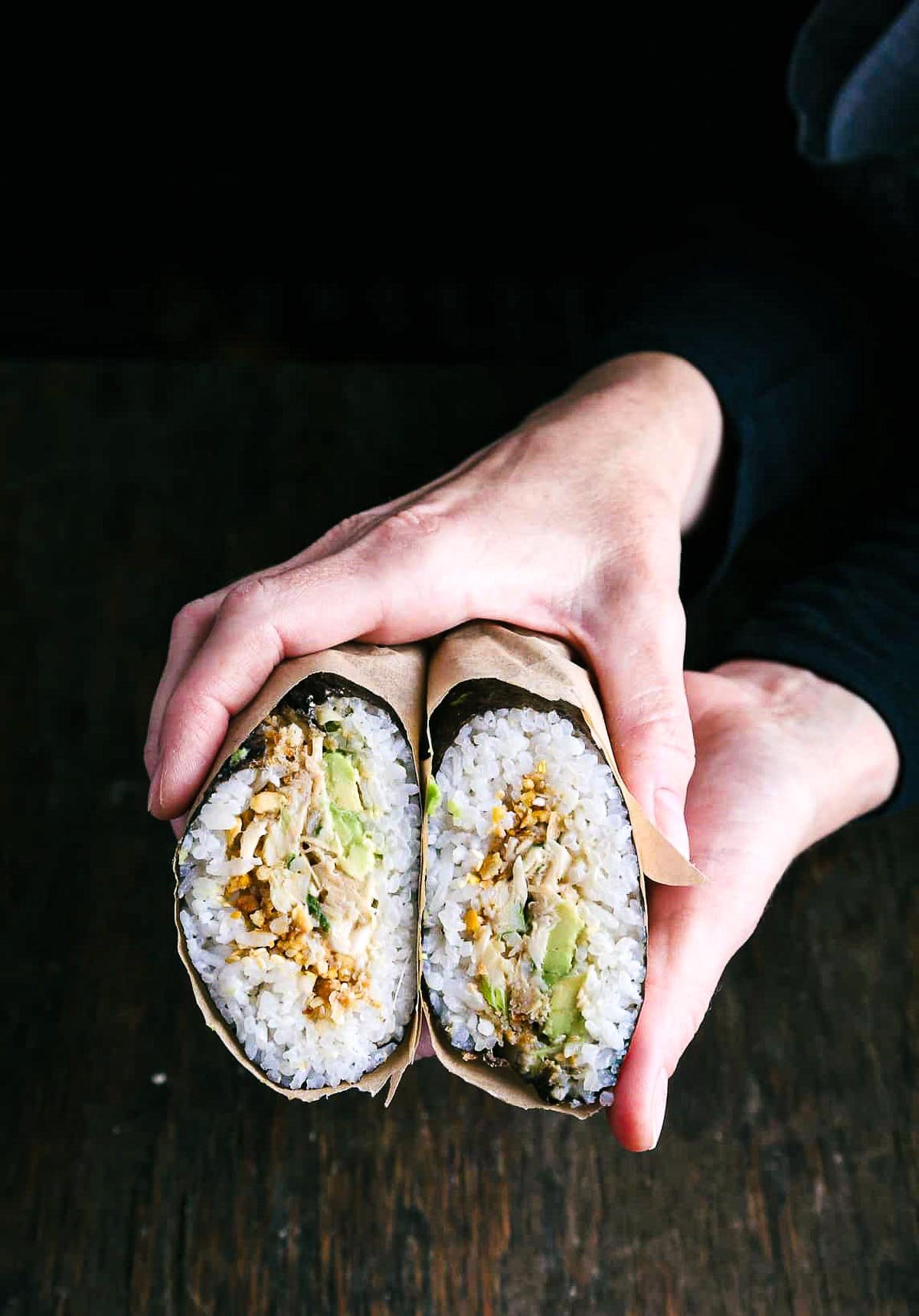 Two hands holding a sushi burrito roll.