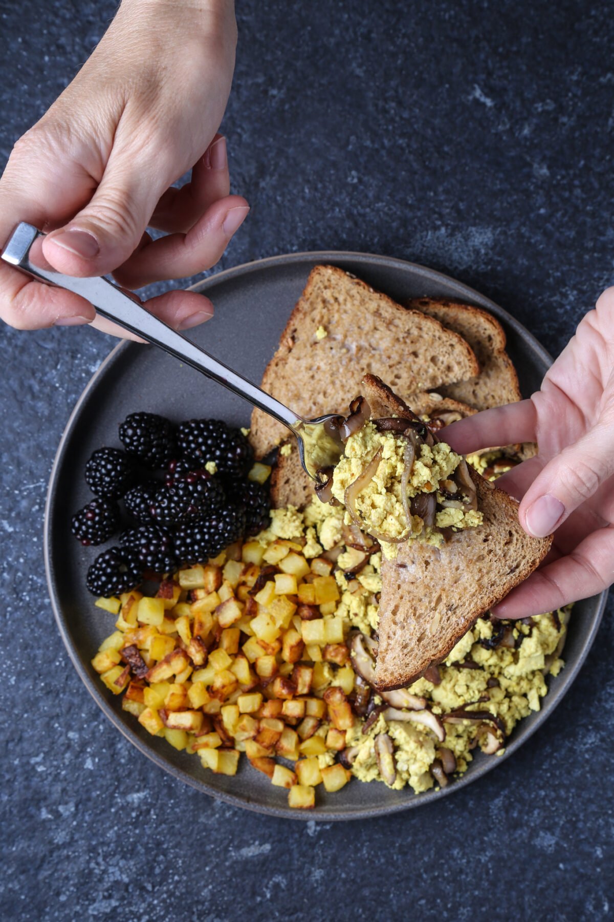 A shot of tofu scramble being held over a piece of toast.