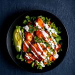 A vegan buffalo cauliflower salad with creamy dressing and avocado.