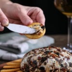 A vegan cheese ball being spread over a cracker.