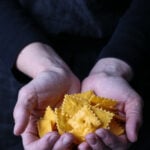Two hands holding baked vegan Cheez Its.