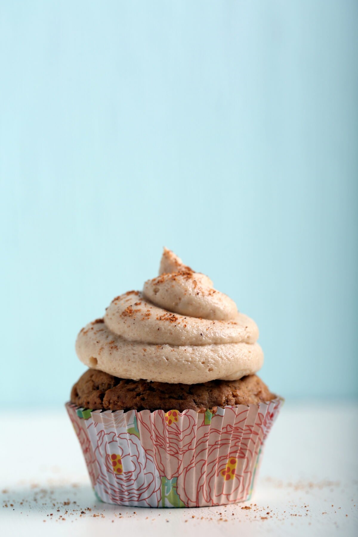 A vegan pumpkin cupcake, topped with frosting.
