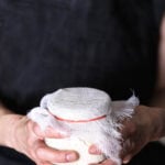 Homemade vegan ricotta cheese culturing in cheesecloth, ready for fermentation.